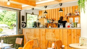 Un área de bar con paneles de madera, una barra con diferentes botellas y sillas de mimbre.
