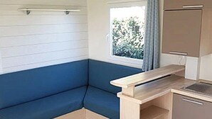 A compact kitchenette with a built-in stove, a small sink, and a cabinet. - ZEcamping 3* piscine chauffée mobil-home 36m2 6 pers (Huelgoat)