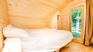 Een houten kamer met een bed, een raam en een deur.
