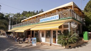 A two-story building with a sign reading "SUPERMARKET" on the upper level. - ZEcamping 3 étoiles familial 200m plage piscine locatif TV clim 28m2 (Calella)