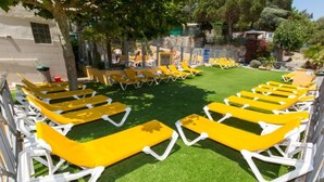 A poolside area with rows of yellow sun loungers and a green artificial turf. - ZEcamping 3 étoiles familial 200m plage piscine locatif TV clim 28m2 (Calella)