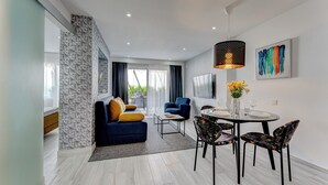 A modern living room with a sofa, coffee table, and dining area with chairs and a table. - BAL One bedroom apartment Adults Only (101) (Arona)