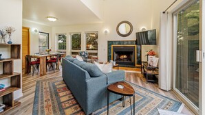 Una sala moderna con un sofá, una chimenea, un televisor y un comedor con sillas y una mesa.