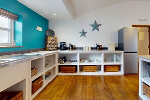 A modern kitchen with white cabinetry, wooden flooring, and decorative star wall art.