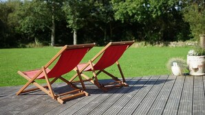 Dos sillas de madera con cojines rojos sobre una terraza de madera.