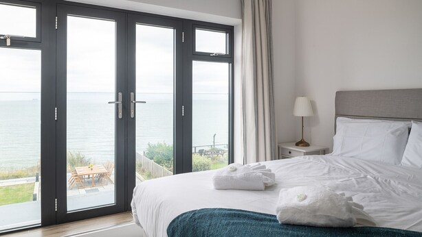 Et soveværelse med en stor skydedør, der fører ud til en balkon med havudsigt.