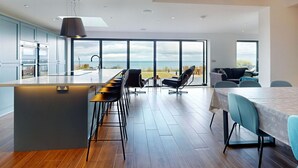 Et moderne køkken med en stor ø, barstole og havudsigt.