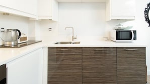 A modern kitchen with white cabinets, a stainless steel sink, a microwave, and a kettle. - Eleven - One Bedroom Cottage, Sleeps 2 (Deganwy)