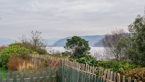 A coastal view with a wooden fence and greenery. - Eleven - One Bedroom Cottage, Sleeps 2 (Deganwy)
