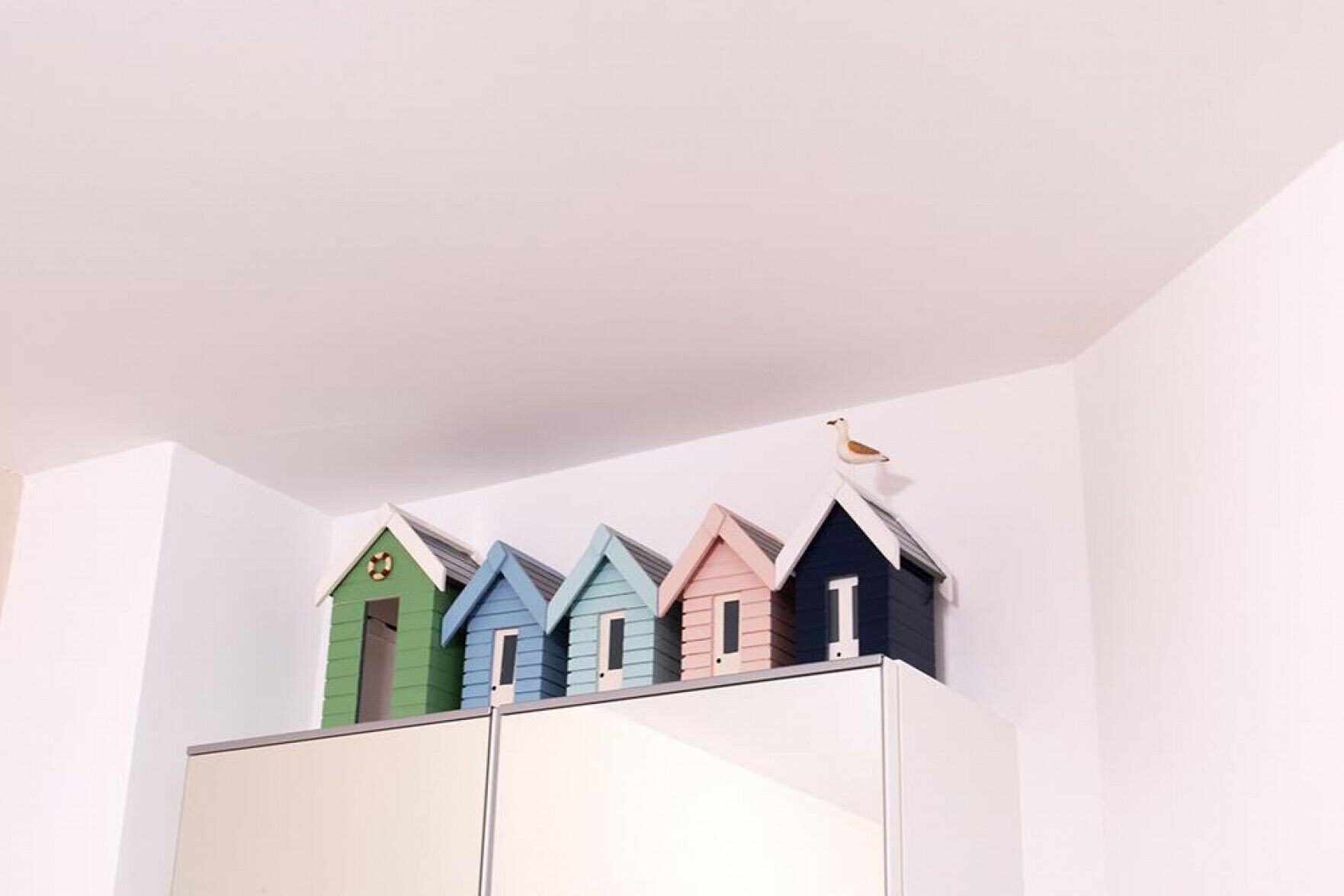 A row of colorful wooden houses on top of a white cabinet.