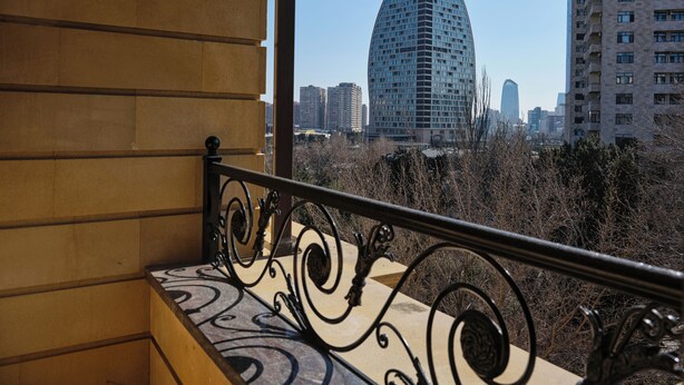 Ein Balkon mit schmiedeeisernem Geländer mit Blick auf eine Stadtlandschaft mit modernen Gebäuden.