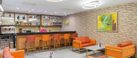 A modern bar area with a bartender, orange seating, and a variety of liquor bottles.