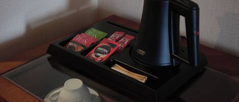 A coffee maker with a tray of coffee pods and a cup on a table.