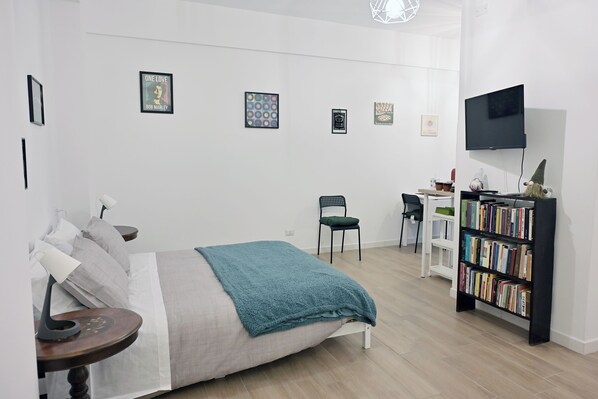 A modern bedroom with a bed, bedside table, and a bookshelf.