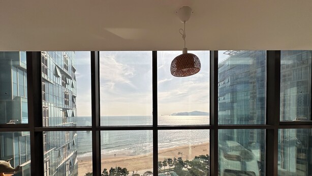 A modern room with large windows overlooking a beach and cityscape.