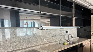 A modern kitchen with granite countertops, stainless steel appliances, and black cabinetry.