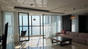 A modern living room with a large window, a sofa, a coffee table, and a television.