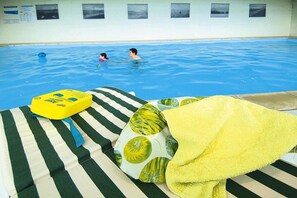 A poolside area with a lounge chair, a yellow flotation device, and a towel.