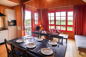 A dining area with a table set for four, a television, and a view of the outdoors.