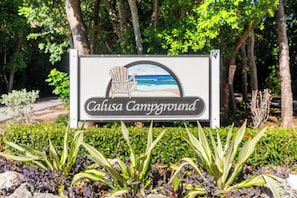 A sign for Calusa Campground with a beach scene illustration. - Happy in the Keys Tiny Home-in Key Largo. (Key Largo)
