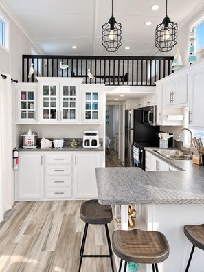 A modern kitchen with white cabinetry, a marble countertop, and a central island with stools.