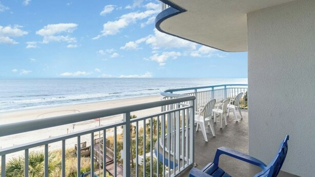 A balcony with a view of the beach and ocean.