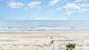 A beach with a flag, sandy dunes, and the ocean.