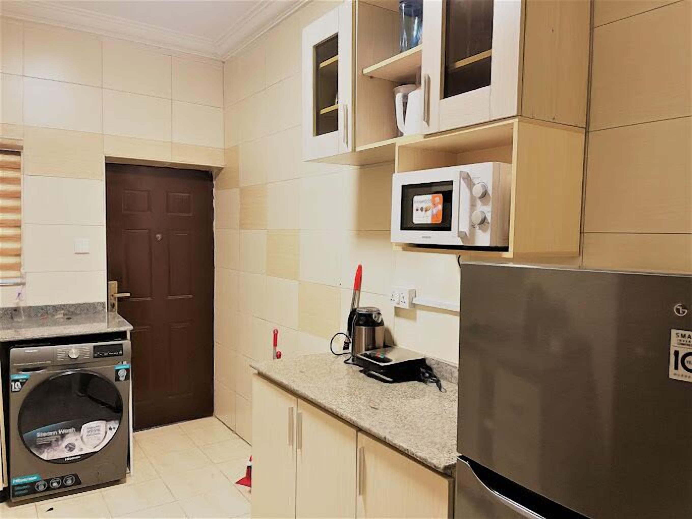 A compact kitchen with a washing machine, microwave, and refrigerator.