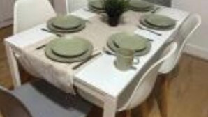 Una mesa de comedor con platos verdes y una planta pequeña en el centro.