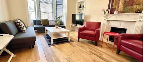 A living room with a sofa, armchairs, a coffee table, a fireplace, and a television.