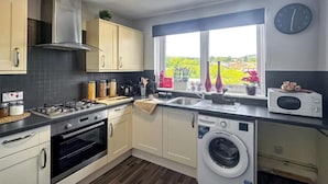 A modern kitchen with a stove, oven, sink, and washing machine. - Brand New Scotland home 3rooms near Glasgow
 (Hardgate)