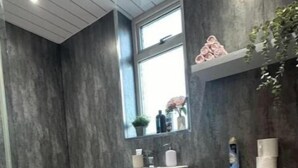 A modern bathroom with a large window, a white sink, a toilet, and a grey cabinet. - Holly street house with Separate Entrance, on the Edge of Glasgow
 (Clydebank)