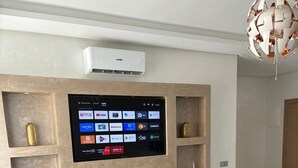Ein modernes Wohnzimmer mit Flachbildfernseher an der Wand, einer Couch und einem Couchtisch.