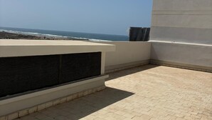 Eine Dachterrasse mit Meerblick, einer Betonwand und einer Lüftungsanlage.