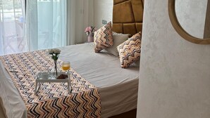 Ein modernes Hotelzimmer mit einem großen Bett, einem Nachttisch mit einem Frühstücksangebot, einem großen Fenster mit Vorhängen und Blick auf die Stadt.