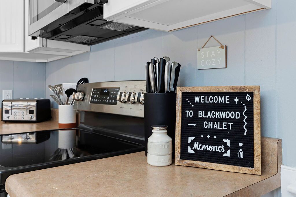 Una encimera de cocina con un tostador, una cafetera y un letrero que dice "WELCOME TO BLACKWOOD CHALET".