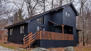 Een chalet met twee verdiepingen en een houten trap naar een balkon.