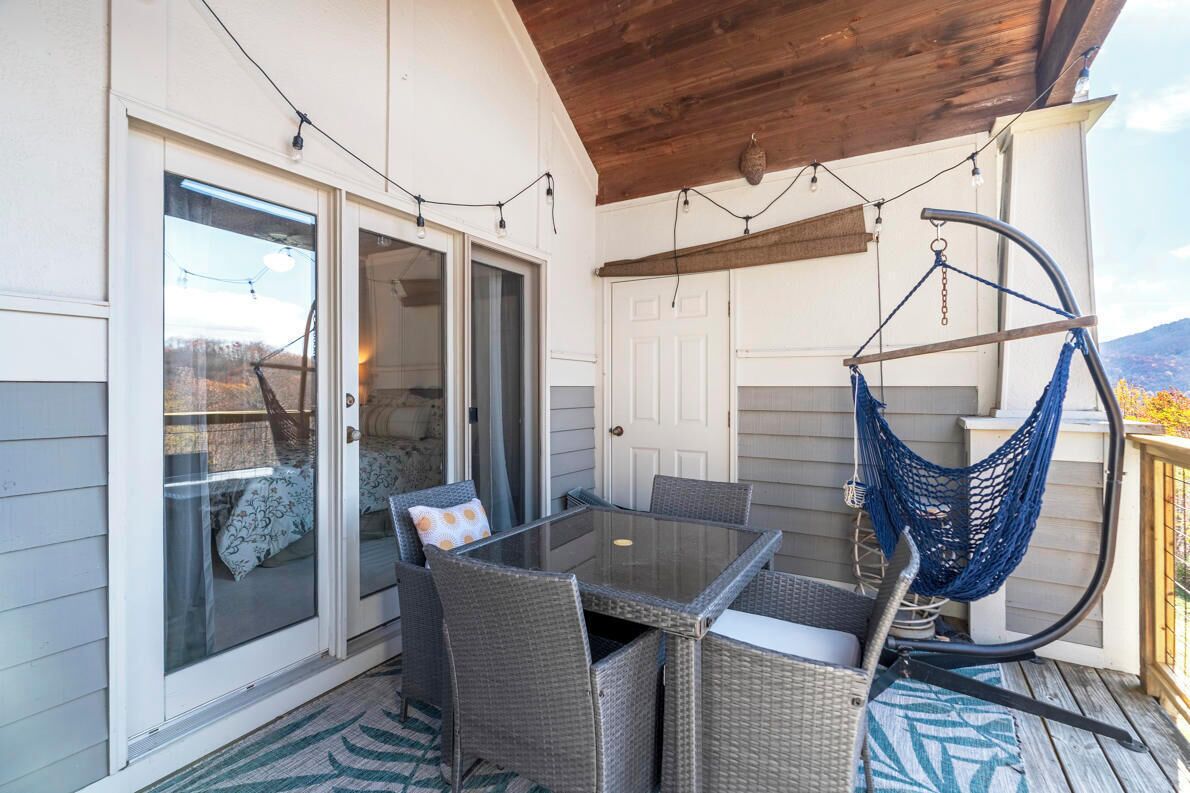 A covered patio with a glass table and wicker chairs, a hammock, and a sliding glass door.