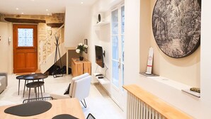 Ein modernes Wohnzimmer mit Essbereich, einer Treppe und einem großen Wandbild.