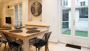 Ein moderner Essbereich mit einem Holztisch, schwarzen Stühlen und einem großen Wandbild.