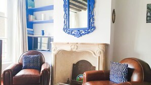 A living room with two leather armchairs, a glass coffee table, a fireplace, and a blue-framed mirror on the wall. - Large studio - city center - 300 m RER A (Saint-Germain-en-Laye)