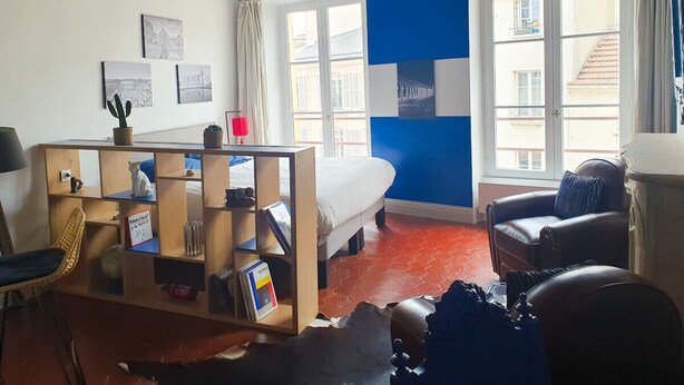 A cozy room with a bed, a desk with a computer, a chair, and a window with curtains. - Large studio - city center - 300 m RER A (Saint-Germain-en-Laye)