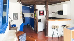 A compact living space with a kitchenette, a dining area, and a bedroom with a blue door. - Large studio - city center - 300 m RER A (Saint-Germain-en-Laye)