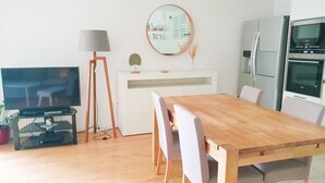 Eine moderne Küche mit Esstisch aus Holz, weißen Schränken und einem eingebauten Backofen.