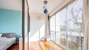 A modern bedroom with a large window, a bed, and a small table. - Beautiful flat 2 rooms near Paris/La Défense (Suresnes)