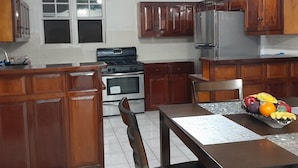Une cuisine avec des meubles de rangement en bois, une cuisinière et un réfrigérateur.