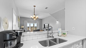 A modern kitchen with a built-in Keurig coffee maker, a double sink, and a chandelier. - Hypnautic East (Gulf Shores)