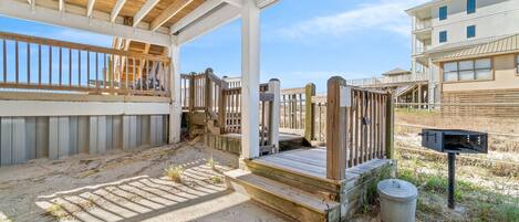 A covered outdoor area with a wooden deck, concrete steps, and a mailbox.