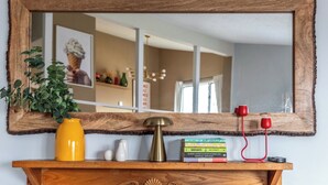 A wooden shelf with a mirror, a yellow vase, a plant, salt and pepper shakers, and a few books. - Sugarbush Condo | Hike, Bike & Explore (Warren)