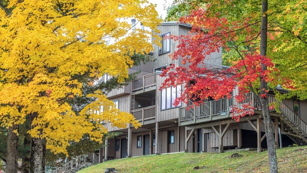 A multi-story building with a wooden exterior and balconies. - Sugarbush Condo | Hike, Bike & Explore (Warren)